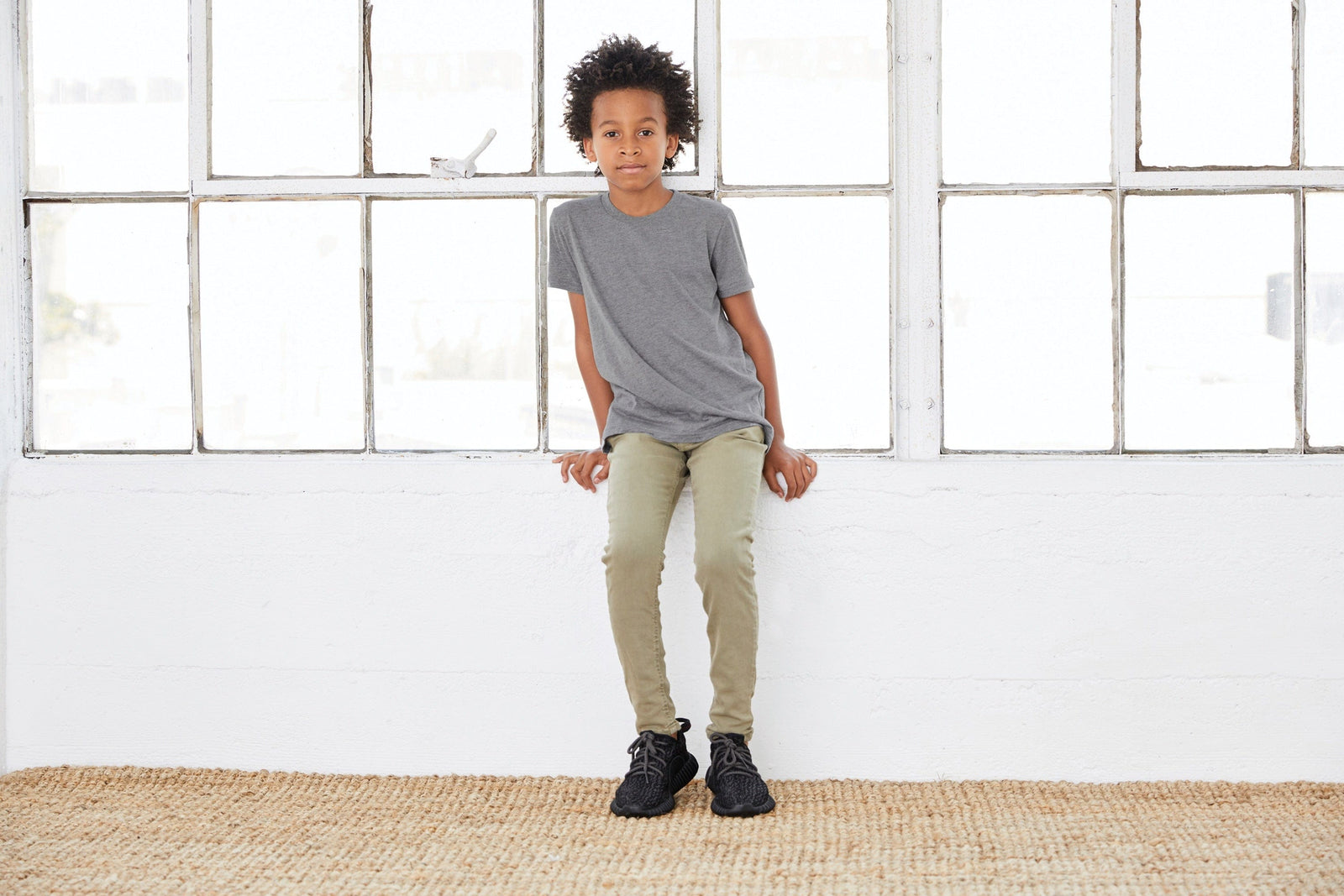 Boy sitting at windowsill, modeling grey t-shirt