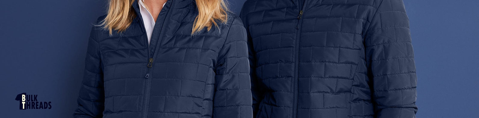 Two people wearing navy blue puffer jackets against a dark blue background.